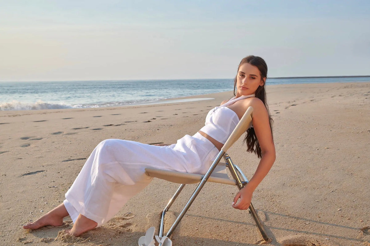 Pantalon Éléonore blanc en lin naturel, à jambes larges et taille haute, porté avec le top Léa sur une plage.