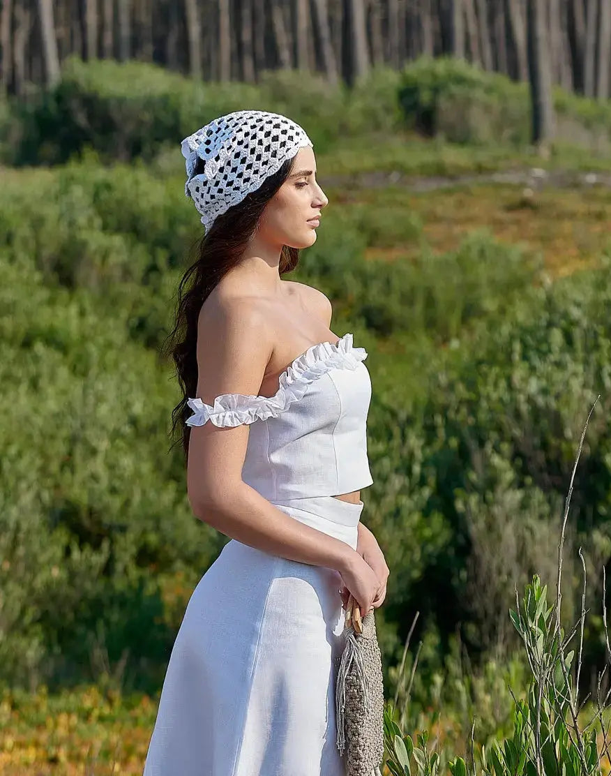 Vue de profil du top Clara blanc en lin naturel, montrant son encolure dégagée et ses manches à volants.